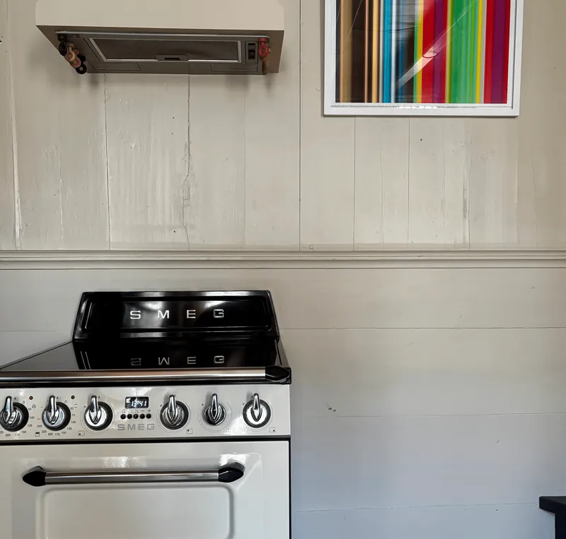 Smeg-fornuis tegen een witte houten wand