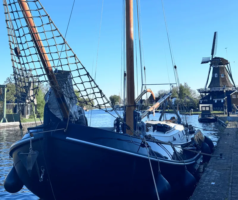 Een platbodem aan de kade met een molen op de achtergrond