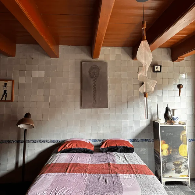 Slaapkamer met tegelwand en houten plafondbalken