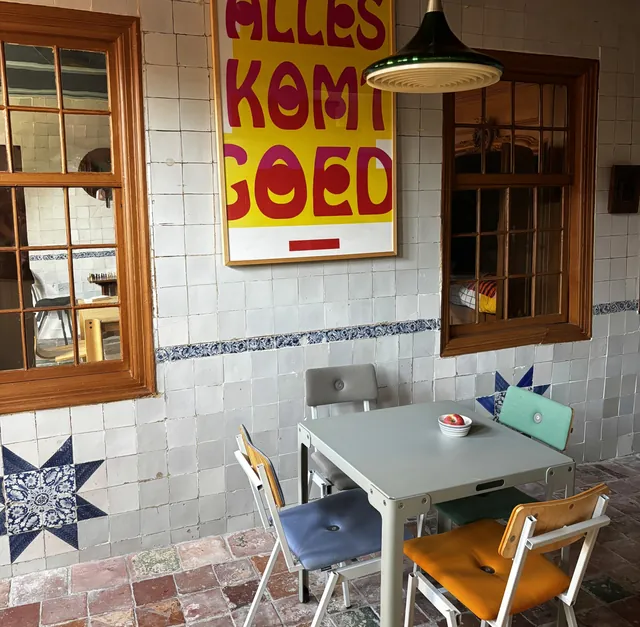 Ontbijttafel tegen een tegelwand met een poster 'Alles komt goed'