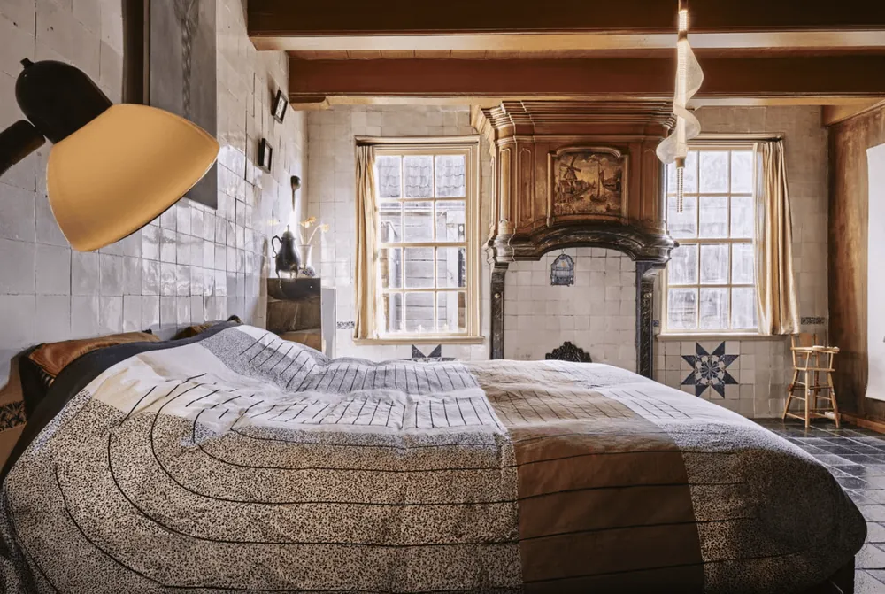 Slaapkamer met antieke schouw en een gele lamp